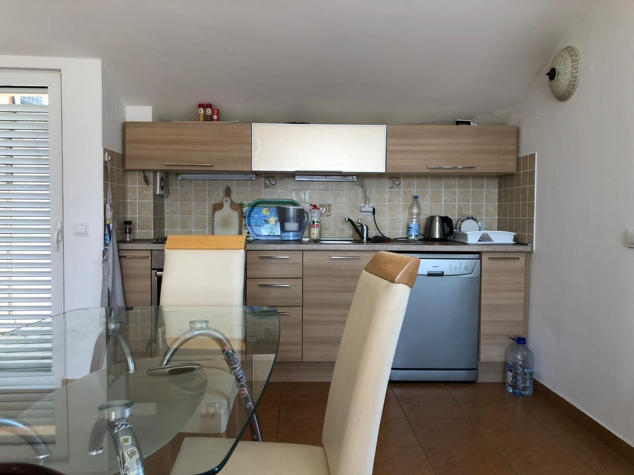 Kitchen with wooden cabinetry and dining area in an apartment in Bečići, Montenegro. Cozy interior with modern appliances.