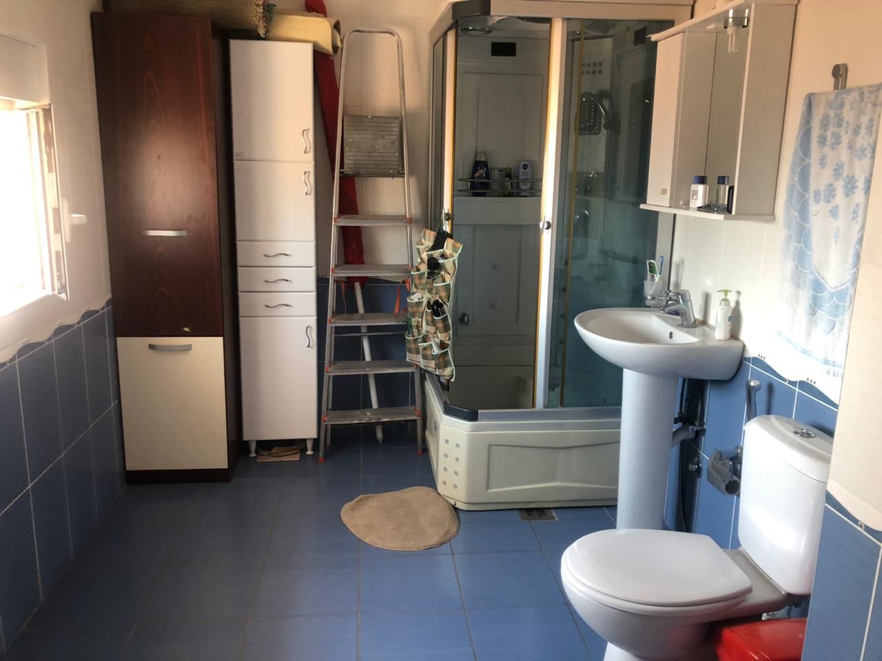 Bathroom in an apartment in Bečići, Montenegro: shower cabin, storage cabinets, sink, and plumbing fixtures.