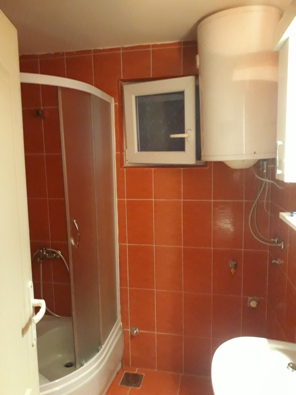 Bathroom with orange tiles, a shower cabin, and a boiler in a house for sale, Zhanitsa, Montenegro.