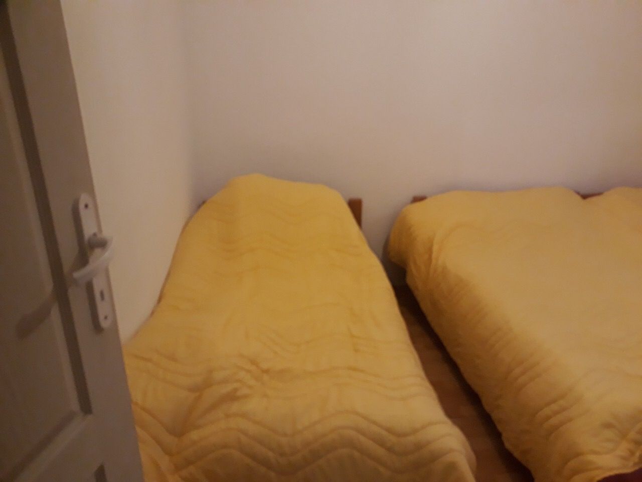 Bedroom with two single beds and yellow bedspreads in a house at the Žanjica resort, Montenegro.
