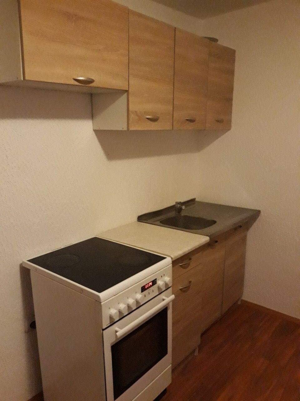 Compact kitchen in a house in Zhanitsa, Montenegro: light-colored cabinets, electric stove and sink, laminate flooring.