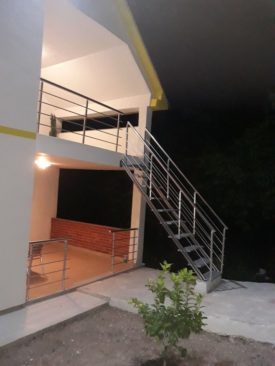 Two-story house with an open terrace and metal staircase in Žanjice, Montenegro, exterior view at dusk.