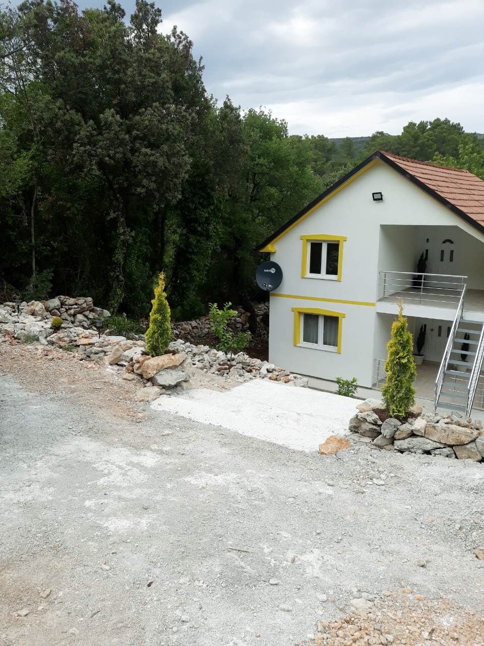 Two-story house with a terrace and garden in Žanjice, Montenegro: front view with an exterior staircase and landscaping.