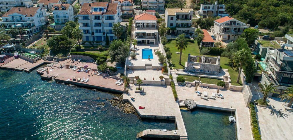 Aerial view of a villa in Krašići, Montenegro: private pool, terrace, private beach, and seaside pier.