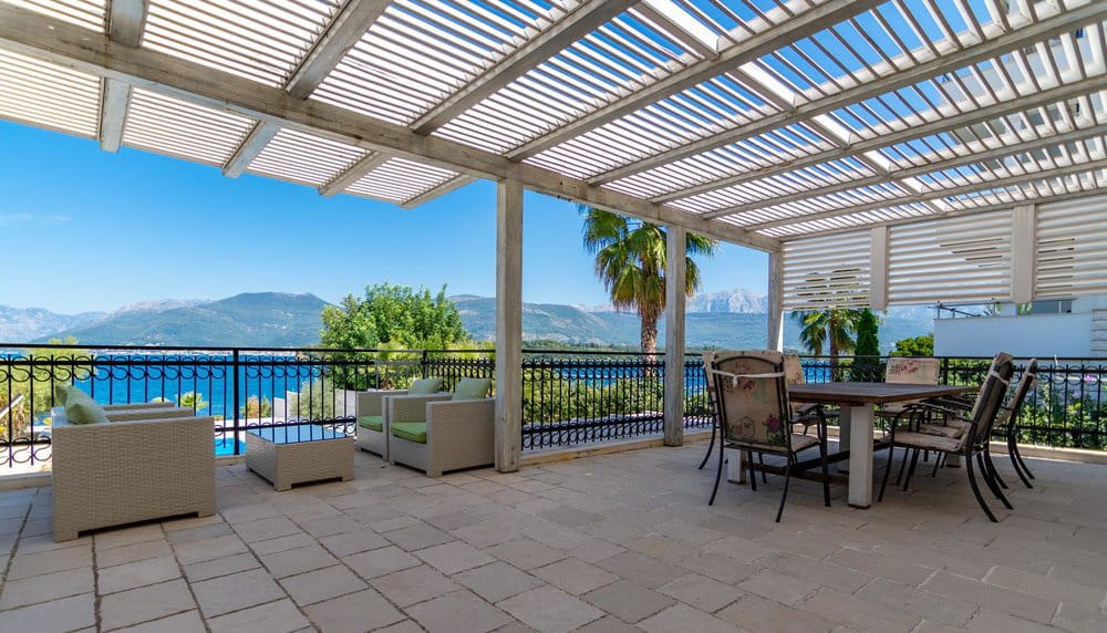 Villa terrace in Krašići, Montenegro: dining area, wicker furniture, and panoramic sea and mountain views.