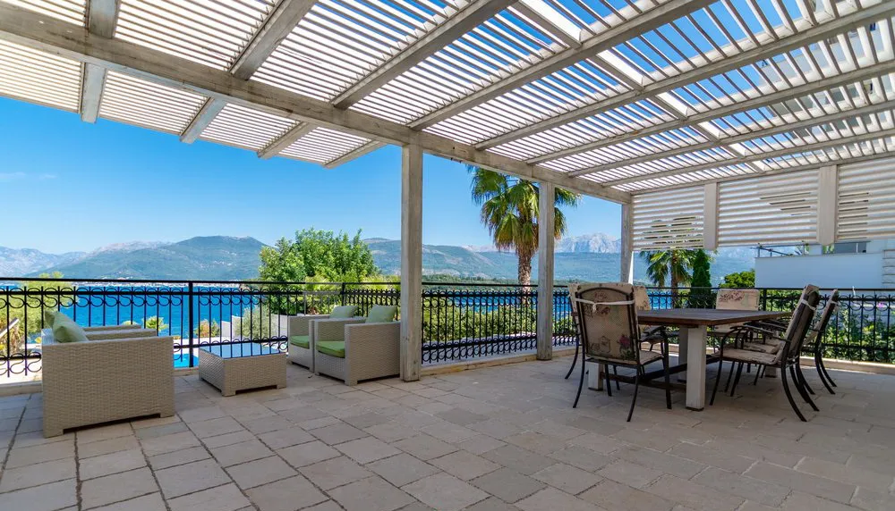 Open terrace with pergola, outdoor furniture, and sea and mountain view.