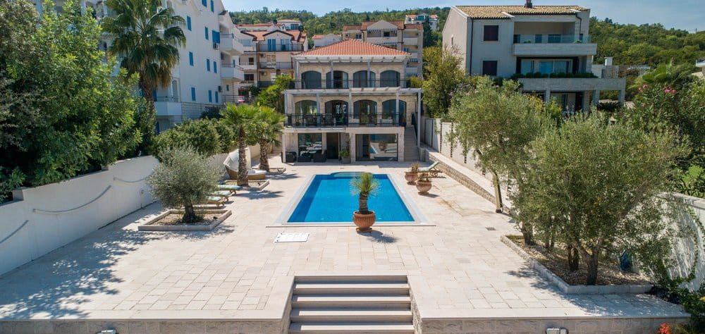 Villa in Krašići, Montenegro: a three-story house with a pool, terrace, and a garden with olive trees on the coast.