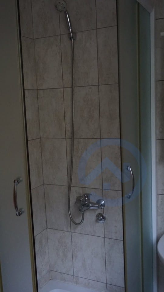 Shower cabin with beige tiles in the bathroom of a house in Kavac, Montenegro. Modern plumbing and finishes.