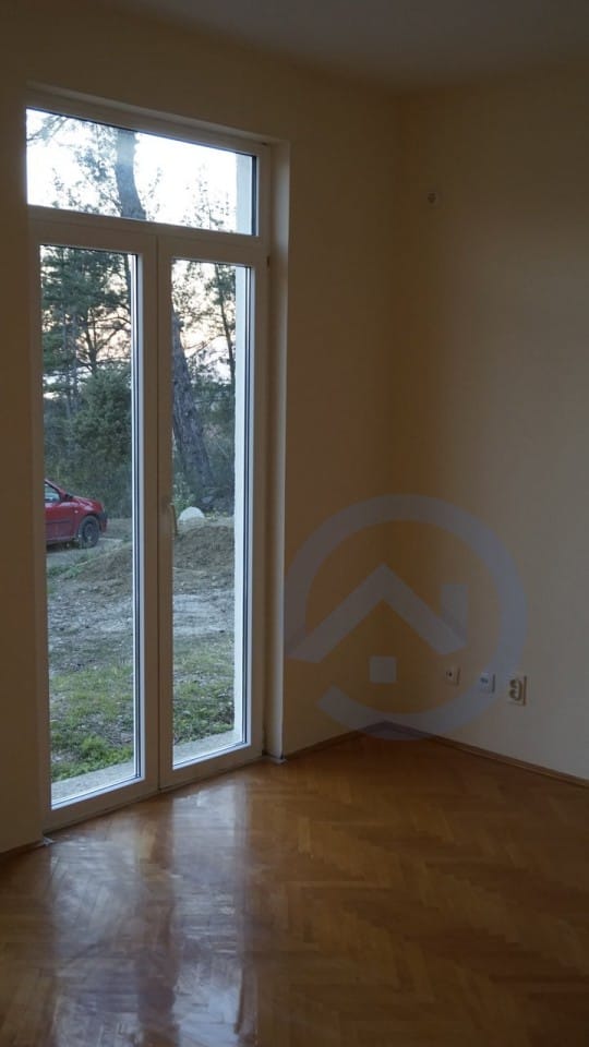 Bright living room with parquet flooring and access to the yard in a house, Kavac, Montenegro. View of pine trees and nature.
