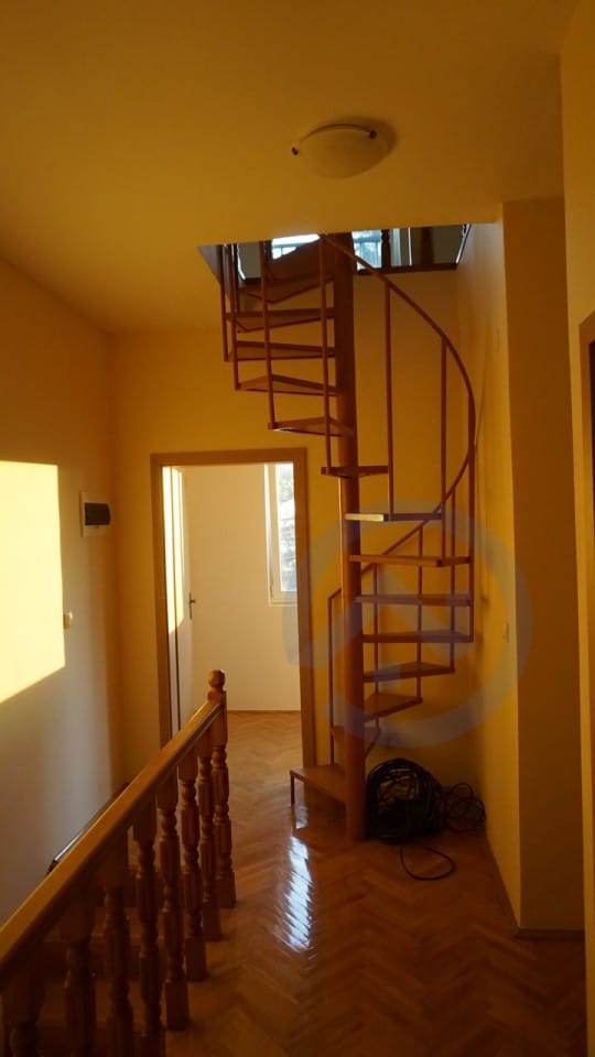 Spiral staircase in the interior of a house in Kavac, Montenegro: wooden parquet, classic railings, and light walls.