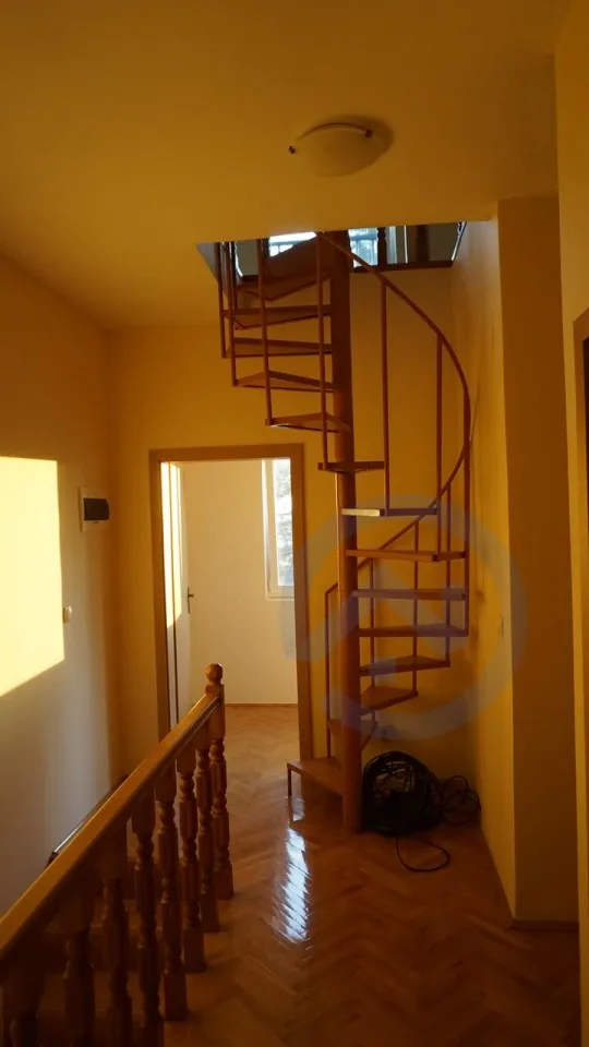 Interior hallway featuring a wooden spiral staircase, wooden railings, and herringbone parquet flooring.