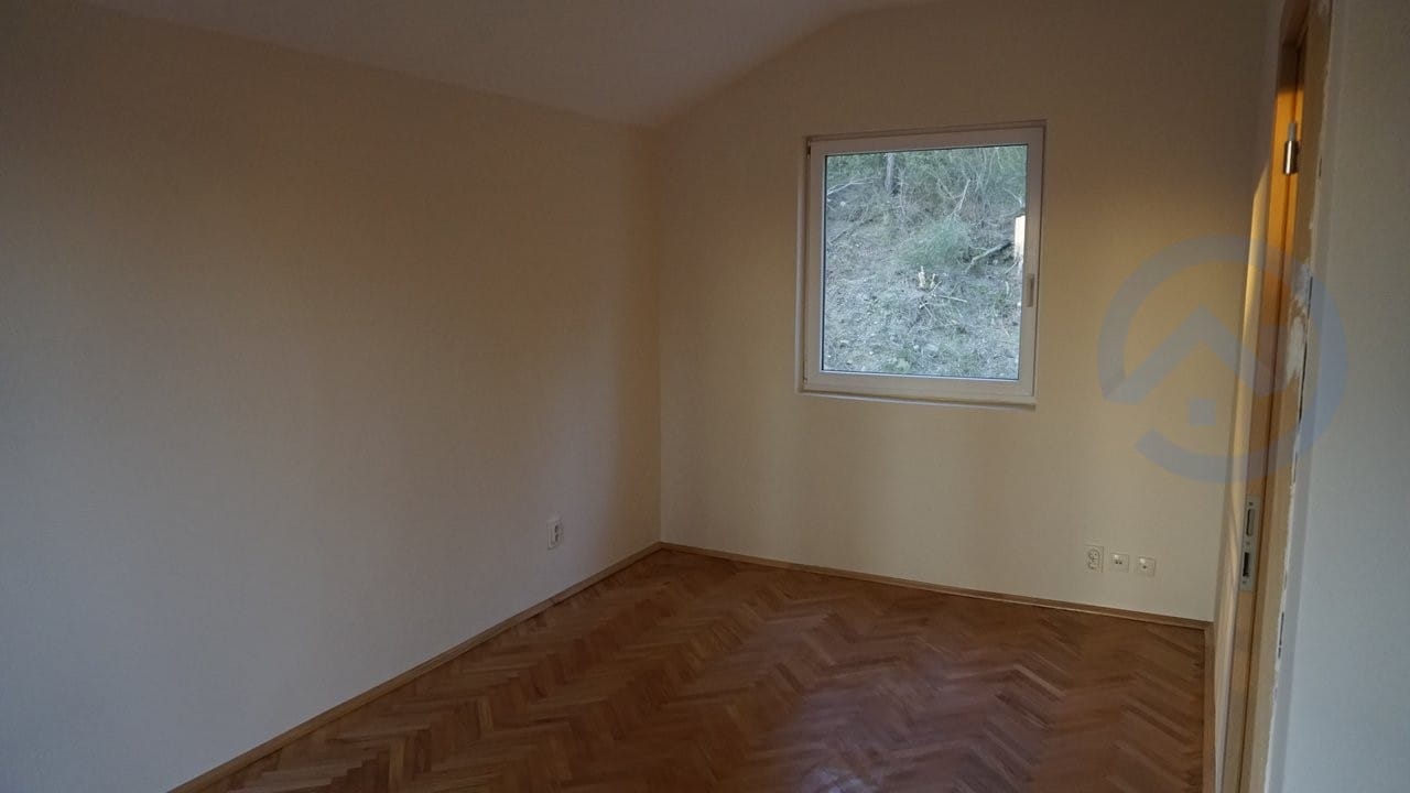 Bright empty bedroom with parquet flooring and a view of nature in a house for sale, Kavac, Montenegro.