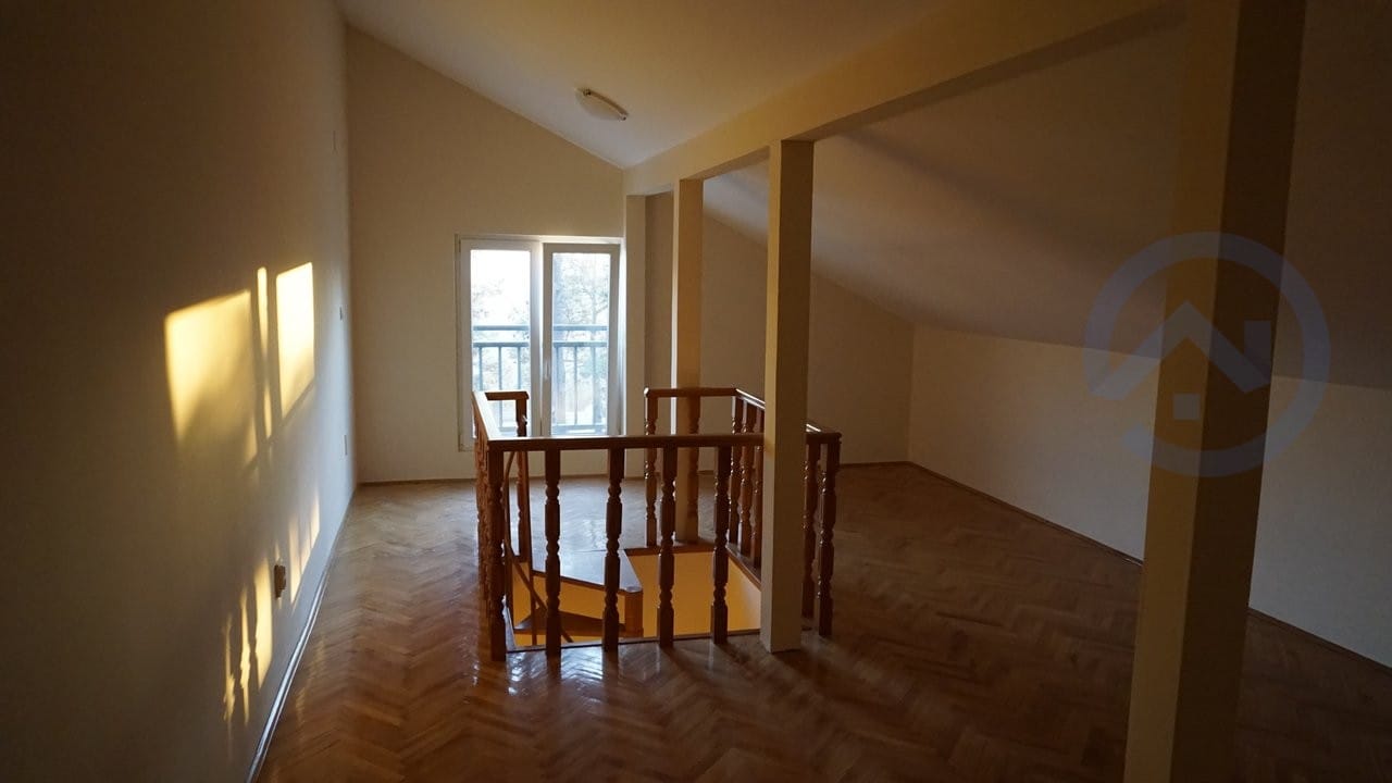 Attic living room with parquet flooring and a wooden staircase in a house, Kavac, Montenegro. Bright room with access to the balcony.