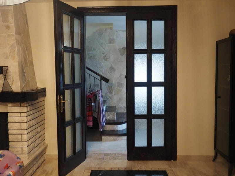 Living room interior with dark wooden doors and a stone fireplace in a villa in Stoliv, Montenegro.