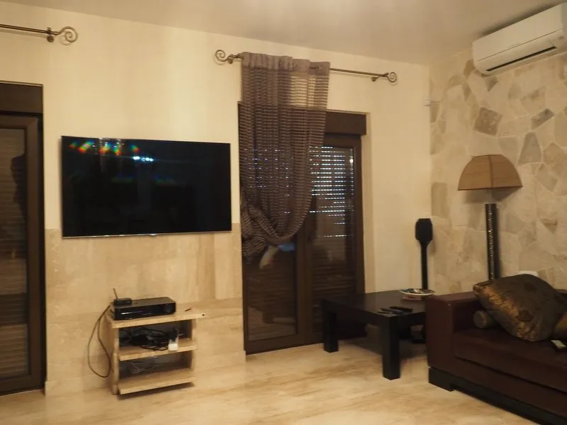 Living room with TV, sofa, coffee table, stone accent wall and floor lamp.