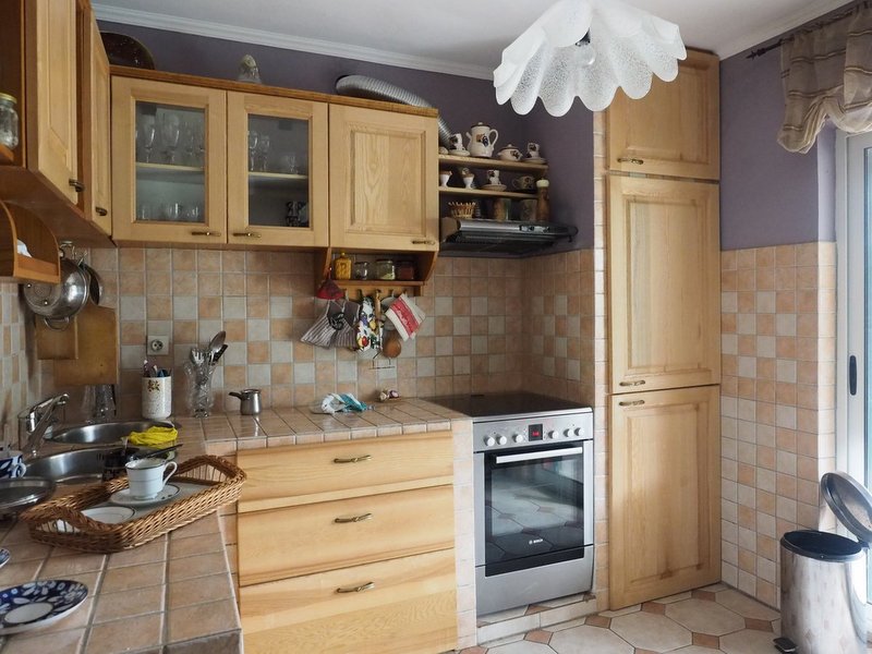 Kitchen with wooden cabinetry and a stove in a villa in Dobrota, Montenegro: interior with tile and access to the terrace.