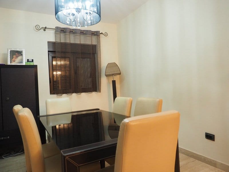 Dining area with a black glass table and light-colored chairs in the villa living room, Stoliv, Montenegro.