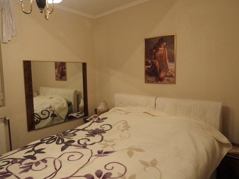 Cozy bedroom with a double bed and mirror in a villa in Dobrota, Montenegro. Bright interior, classic style.