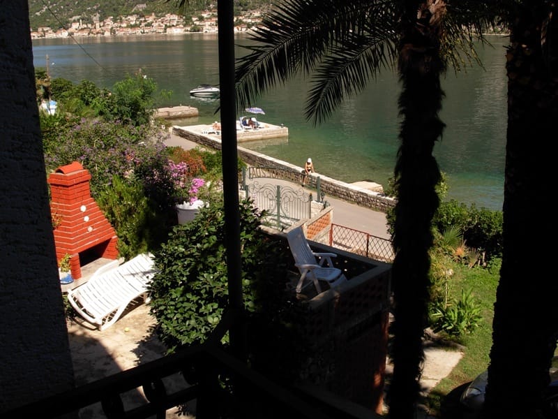 View from the balcony of a house in Stoliv, Montenegro: private garden with barbecue, sun loungers, and direct access to the sea in the Bay of Kotor.