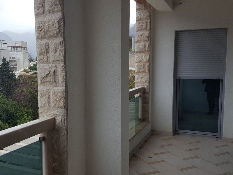 Balcony with stone finishes and mountain views in an apartment, Dobrota, Montenegro. Modern glazing and tile flooring.