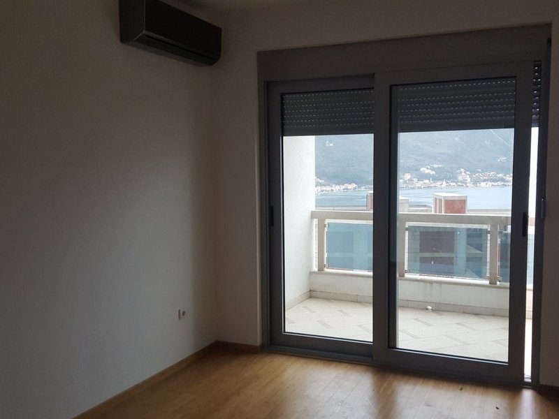 Living room with access to the balcony and sea view in an apartment, Dobrota, Montenegro: panoramic windows and air conditioning.