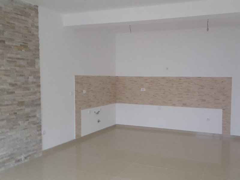 Kitchen in an apartment in Dobrota, Montenegro: light wall finish with decorative stone and tiled floor, space for a kitchen set.
