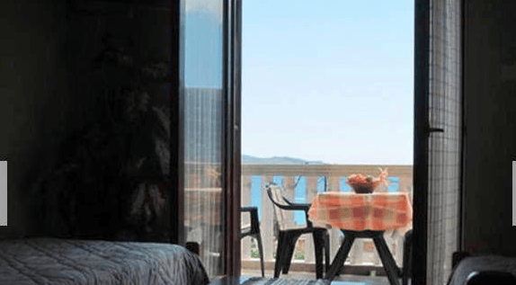 View from the bedroom onto the terrace with furniture and a panoramic sea view in an apartment in Igalo, Montenegro.