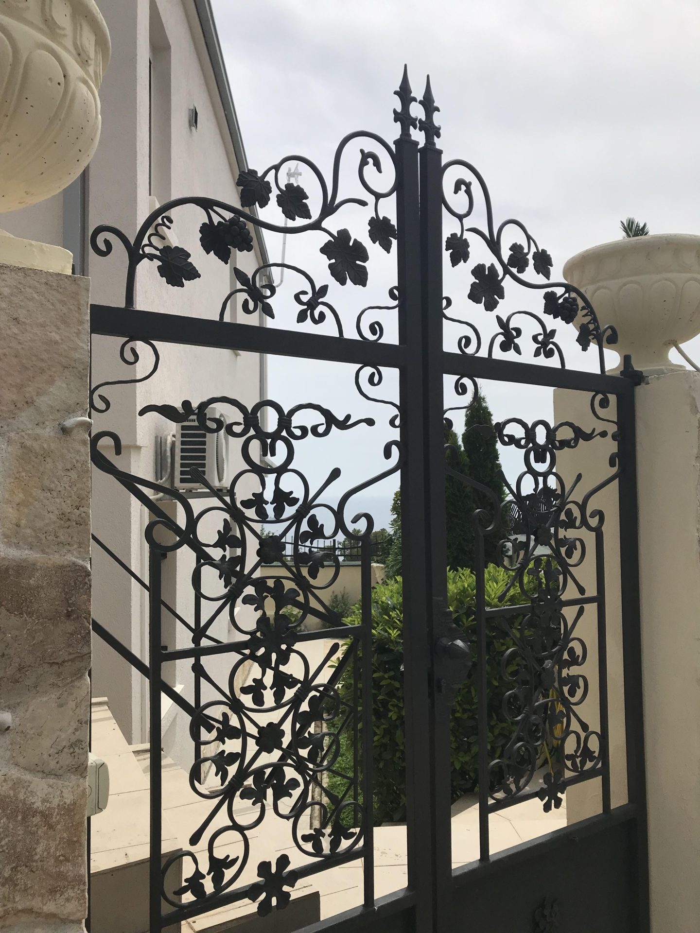 Wrought-iron gate with a floral pattern at the entrance to a house in Bar, Montenegro, with stone facade details.