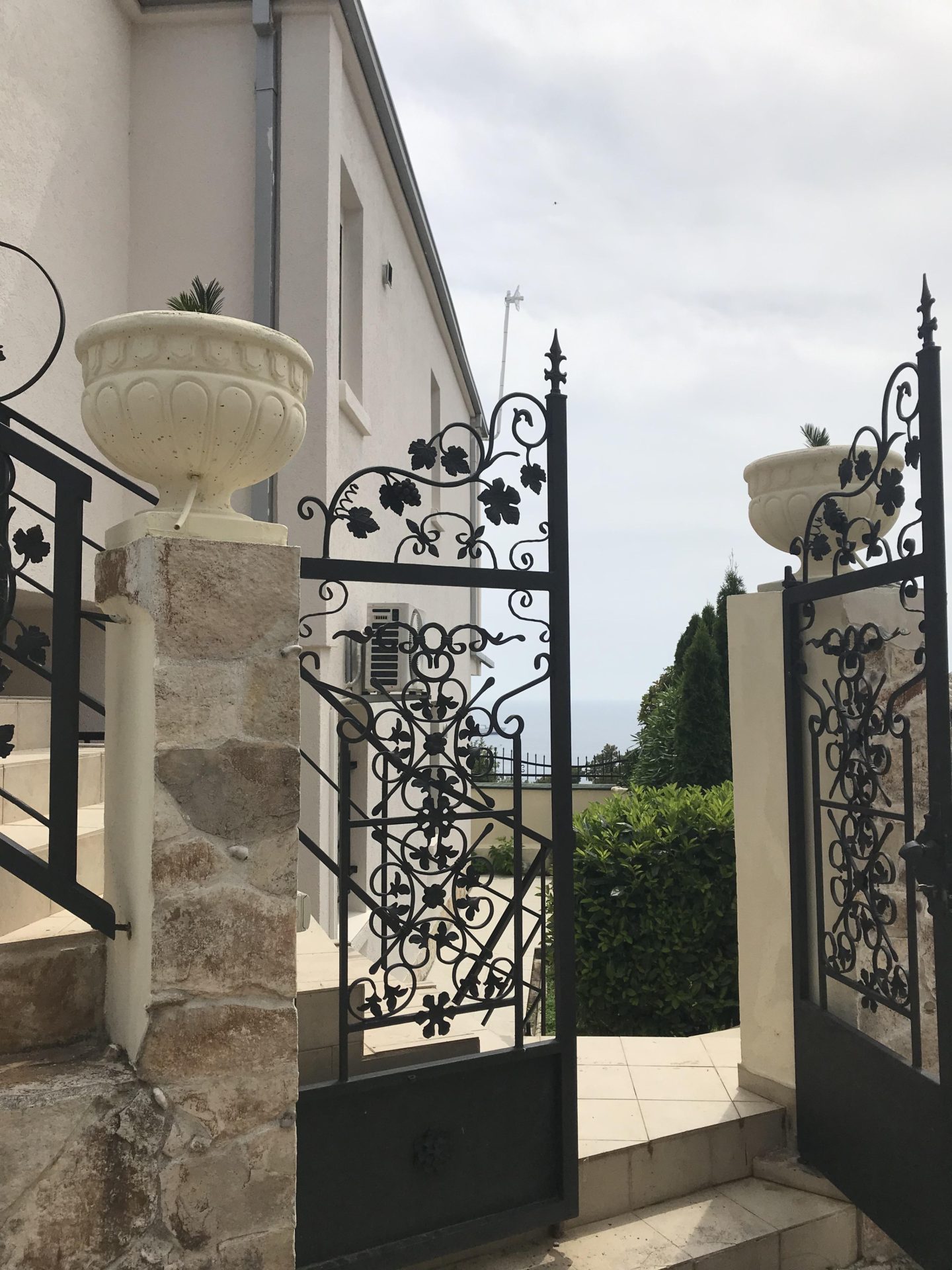 Wrought-iron gate and stone staircase of a house in Bar, Montenegro: view of the yard and garden.