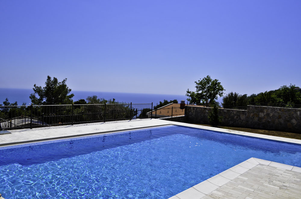 Open-air pool with panoramic sea view at a villa in Shushan, Montenegro, with a stone terrace and fencing.