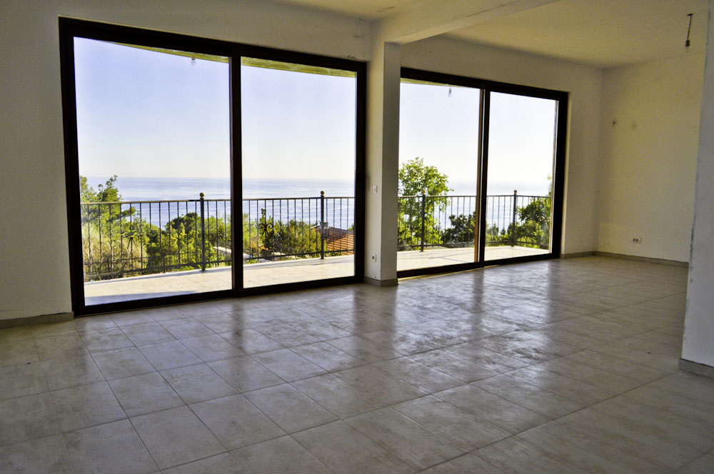 Living room with panoramic windows and sea view in a villa, Shushan, Montenegro: bright finishes and access to the terrace.