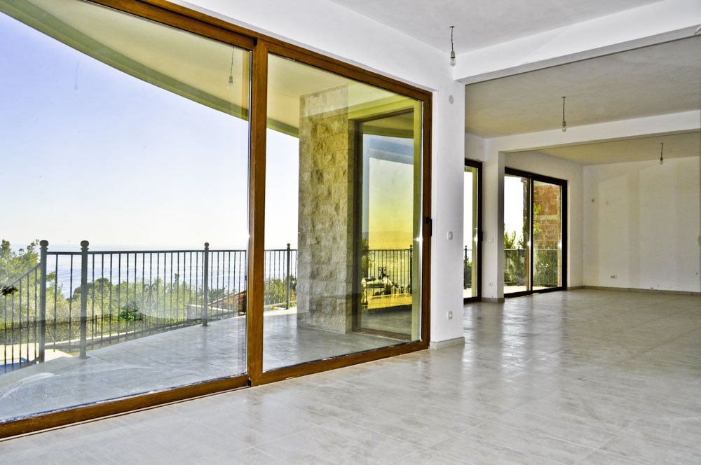 Living room with panoramic windows and sea view in a villa, Shushan, Montenegro. Bright interior with stone finishes.