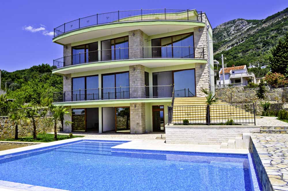 Three-story villa in Shushan, Montenegro, with panoramic windows, terraces, and a private pool against a mountain backdrop.