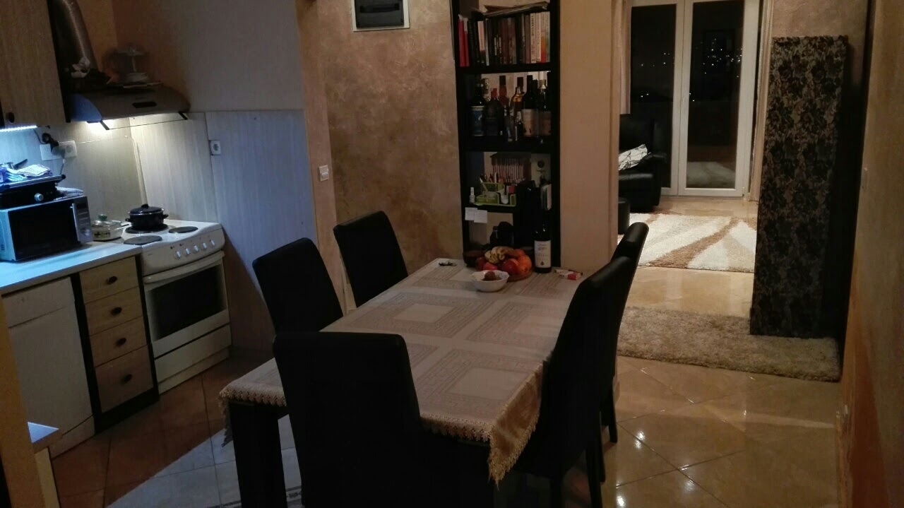 Kitchen-dining room interior in an apartment in Kotor, Montenegro: dining table, kitchen cabinets, and access to the terrace.