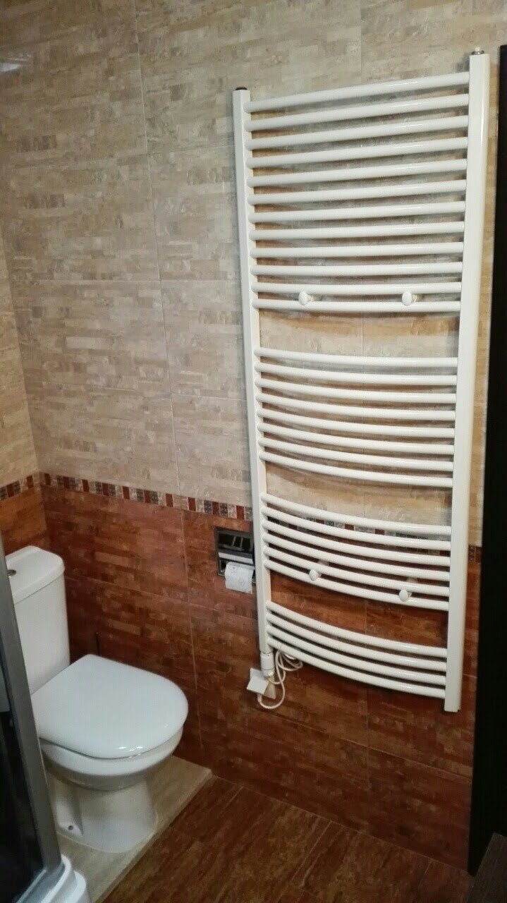 Bathroom in an apartment in Kotor, Montenegro: white electric towel warmer and beige-toned tiles.