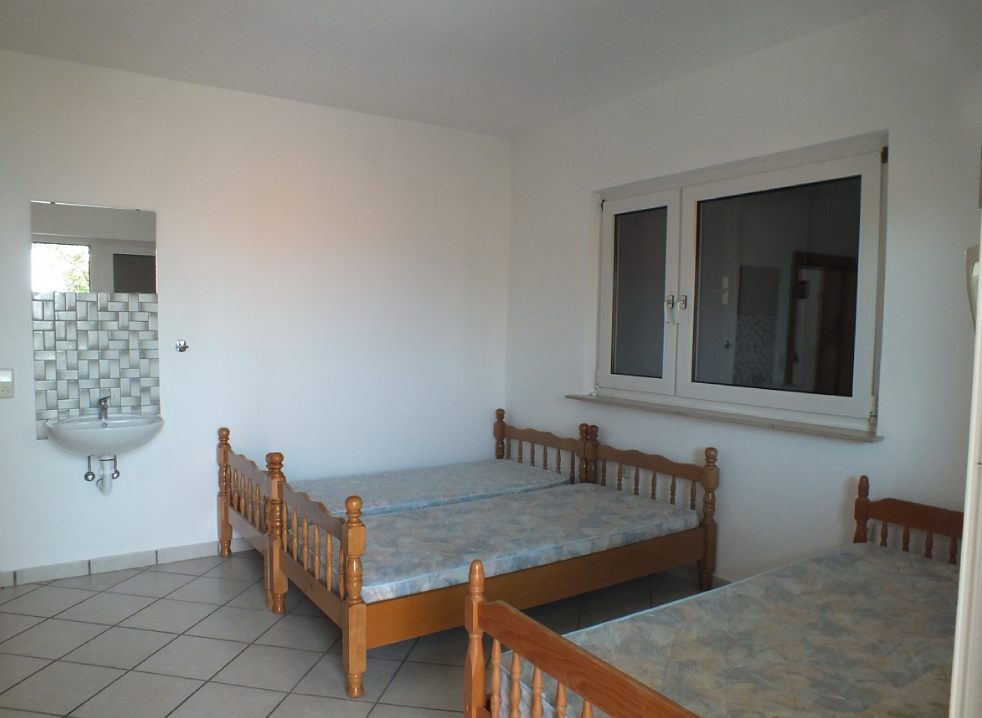 Bedroom with three wooden beds and a sink in a house for sale in Bar, Montenegro.