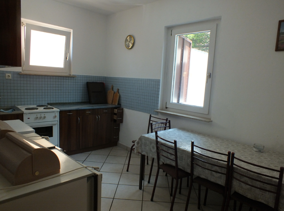 Bright kitchen with dining area in a house, Bar, Montenegro: kitchen cabinets, stove, and table with chairs.