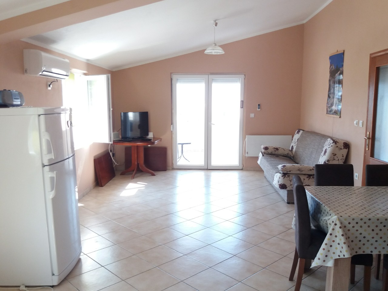 Living room with kitchen in a house in Bar, Montenegro: a bright room with furniture, tiled floor, and access to the terrace.