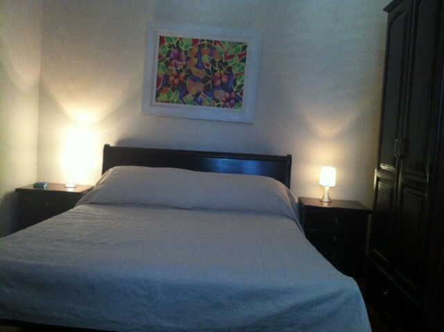 Cozy bedroom with a double bed and dark furniture in a house, Herceg Novi, Montenegro: interior with a painting and lamps.