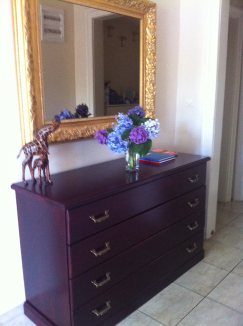 Dark wooden dresser with a mirror in a gold frame and a bouquet of flowers in a home interior in Herceg Novi, Montenegro.