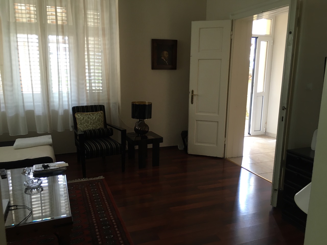 Living room in a house in Herceg Novi, Montenegro: dark parquet flooring, striped armchair, coffee table, and access to the terrace.