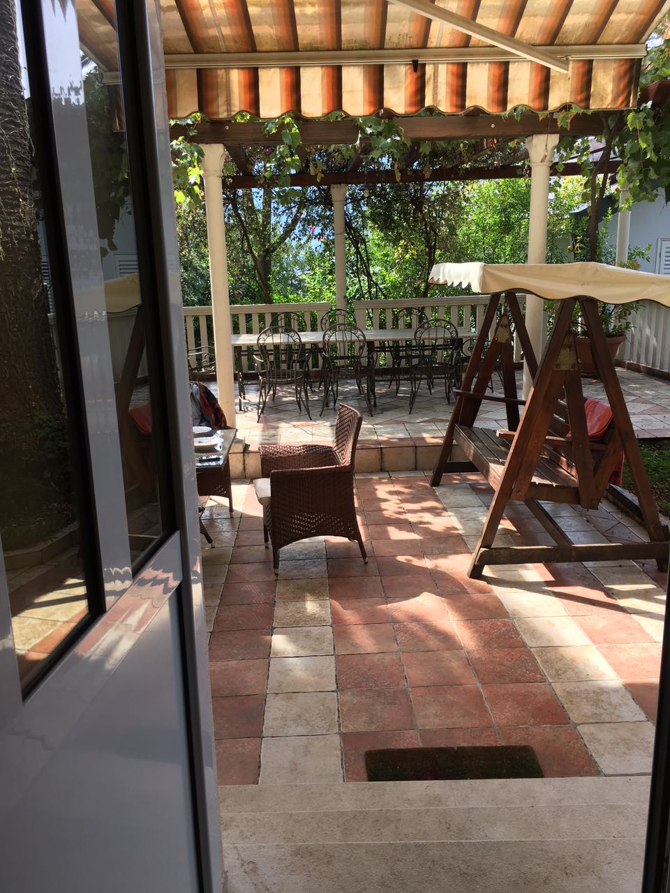 Cozy terrace with garden furniture and a swing in a house, Herceg Novi, Montenegro. View of a shady inner courtyard.