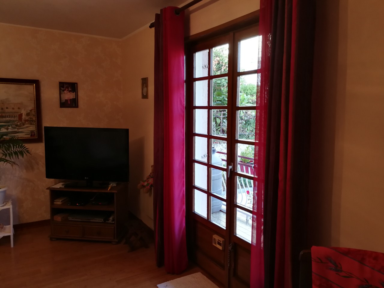 Living room in a house in Tivat, Montenegro: wooden furniture, TV area, and access to a terrace overlooking a green garden.