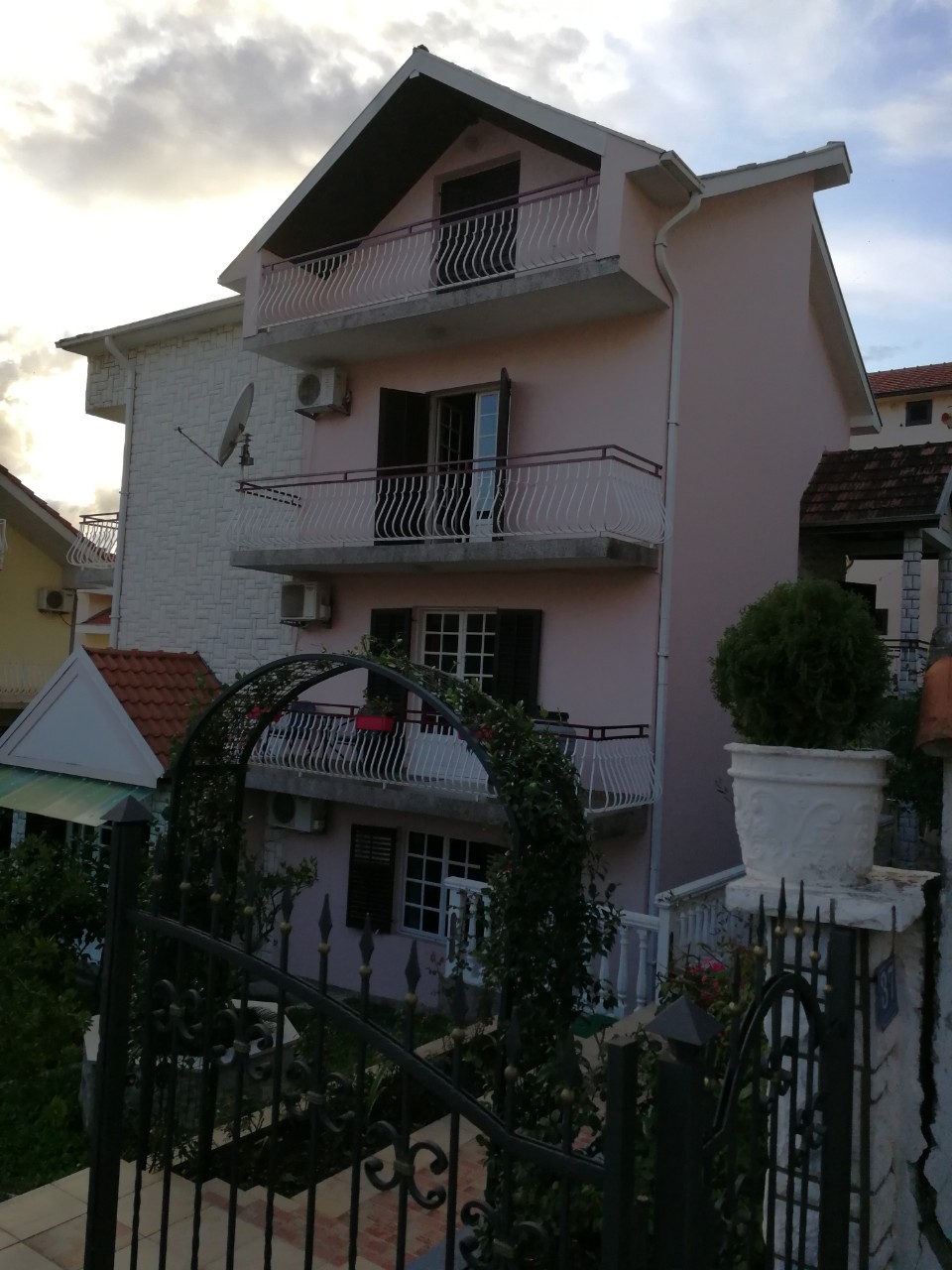 Three-story private house with balconies and wrought-iron gates in Tivat, Montenegro. Front view of the building facade.