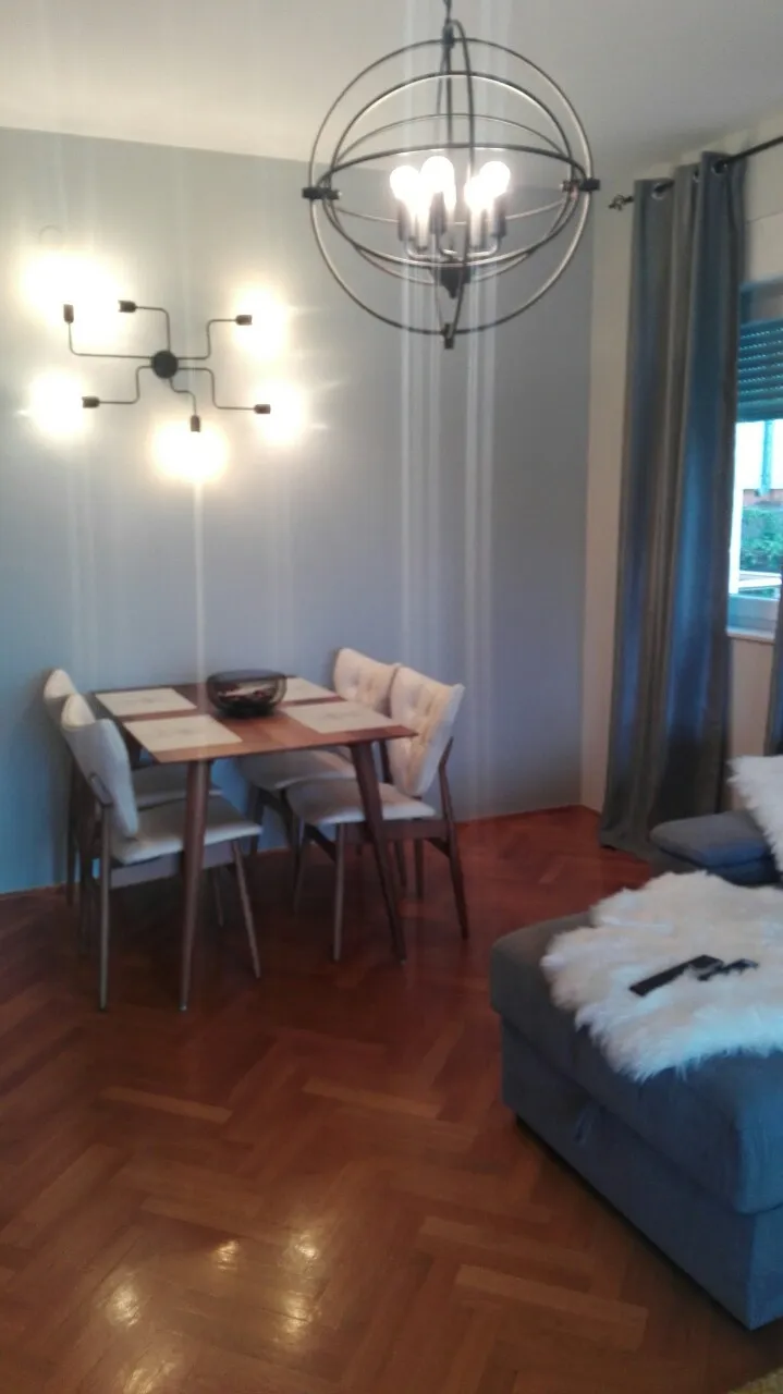 Living room with dining area, grey sofa, parquet floor, and modern sphere chandelier.