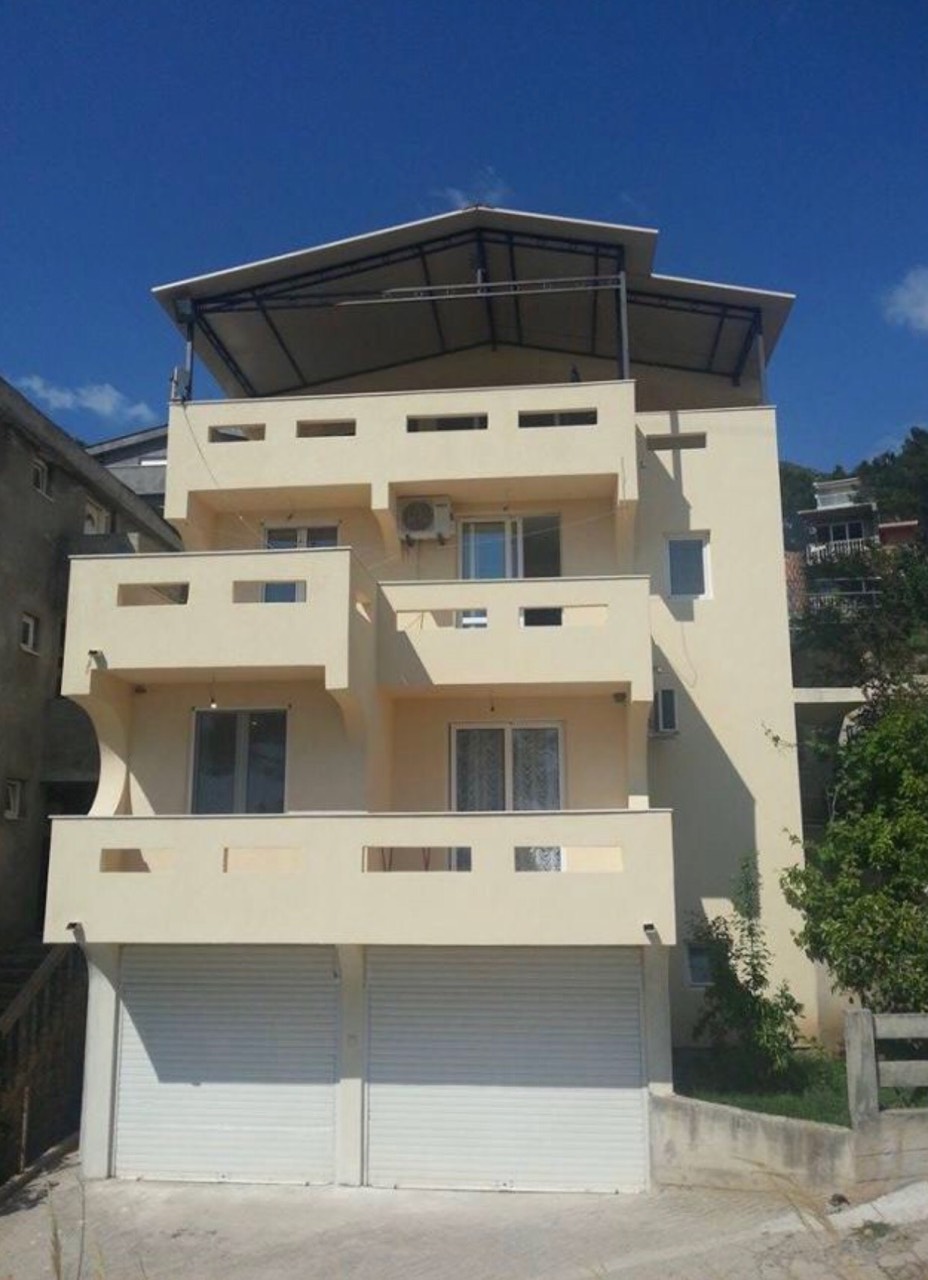 Three-story house in Bar, Montenegro, featuring balconies, a rooftop terrace, and garage roller shutters on the ground floor.