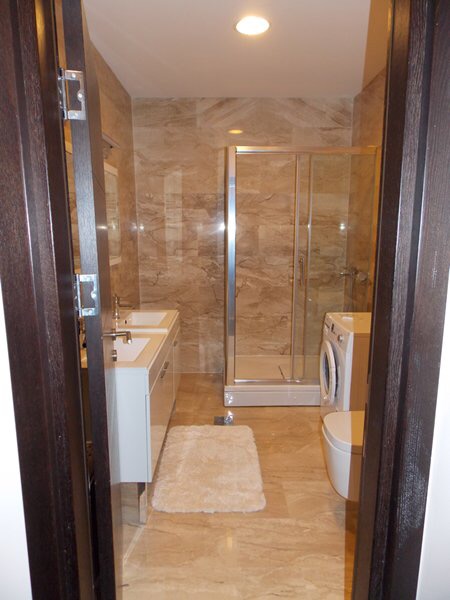 Modern bathroom with a shower cabin and washing machine in an apartment, Budva, Montenegro.