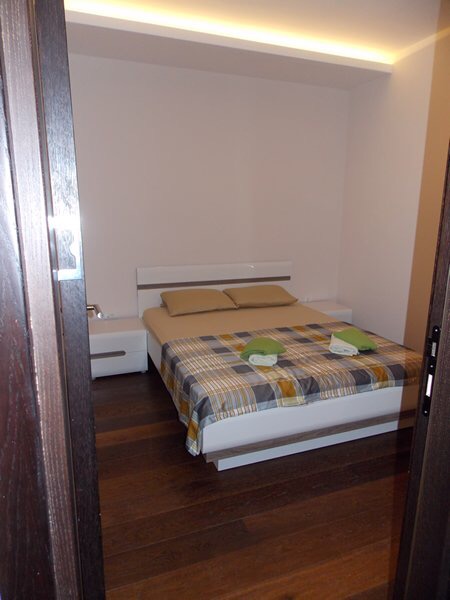 Bedroom with a double bed, white furniture, and parquet flooring in an apartment in Budva, Montenegro.
