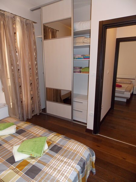 Bedroom in an apartment in Budva, Montenegro: double bed, built-in wardrobe, and a view of the adjacent room.