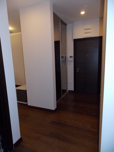 Hallway in an apartment in Budva, Montenegro: dark front door, mirrored sliding wardrobe, and parquet floor.